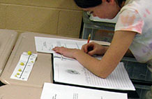 Student writing at desk